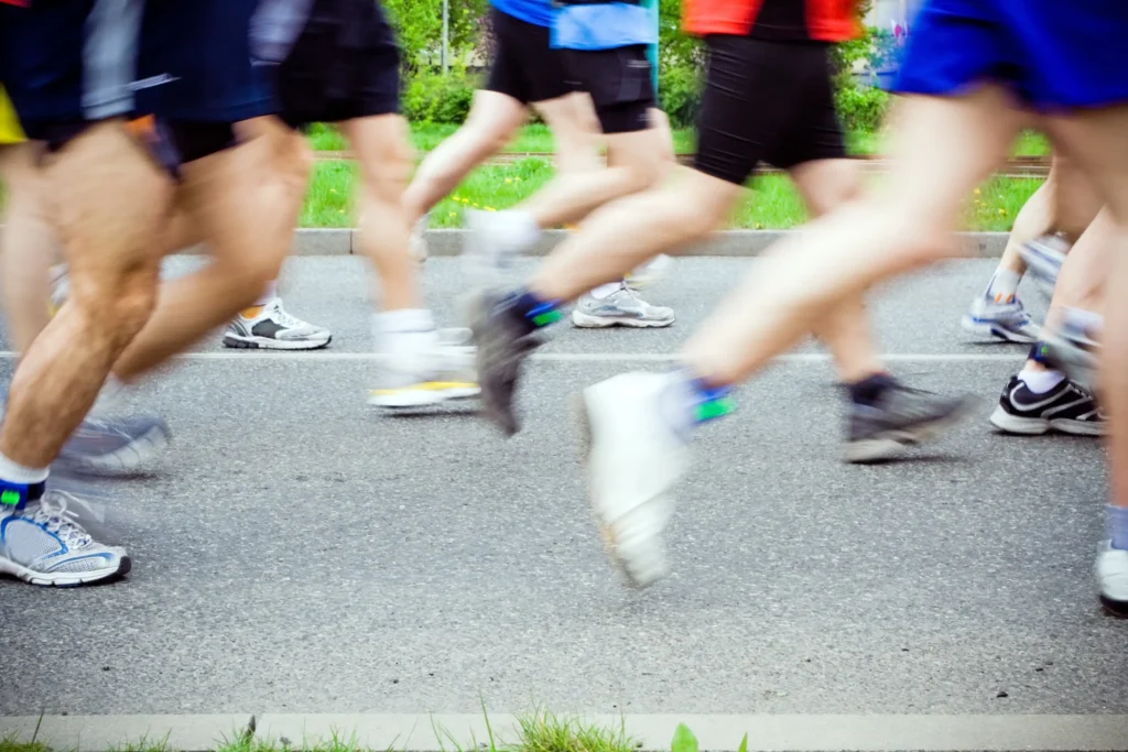 Gambe di podisti in corsa su strada durante una gara o allenamento collettivo