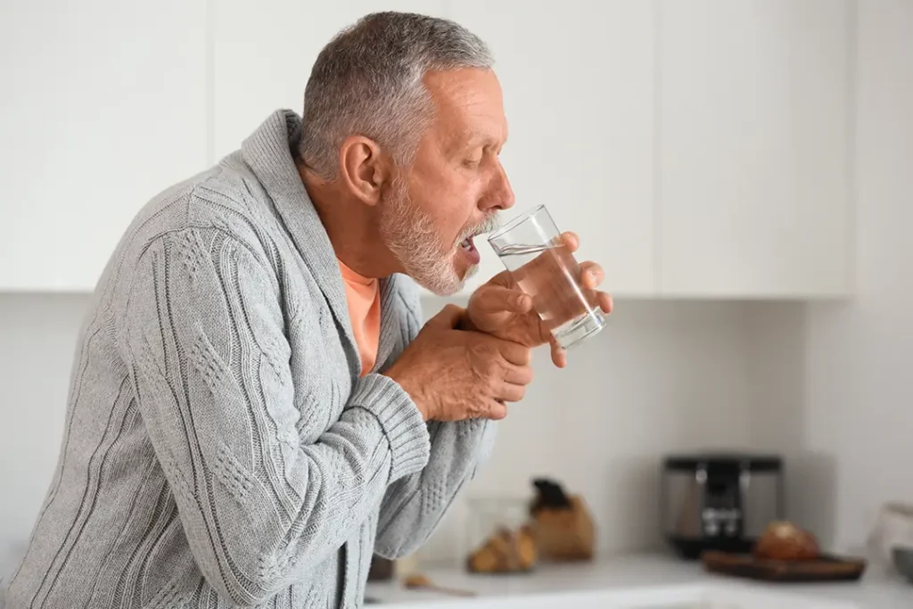 Uomo che beve bicchiere d'acqua