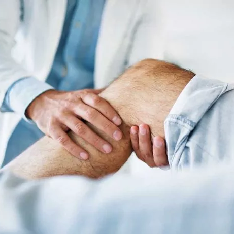 Fisioterapista esegue degli esercizi manuali sul ginocchio di un paziente disteso