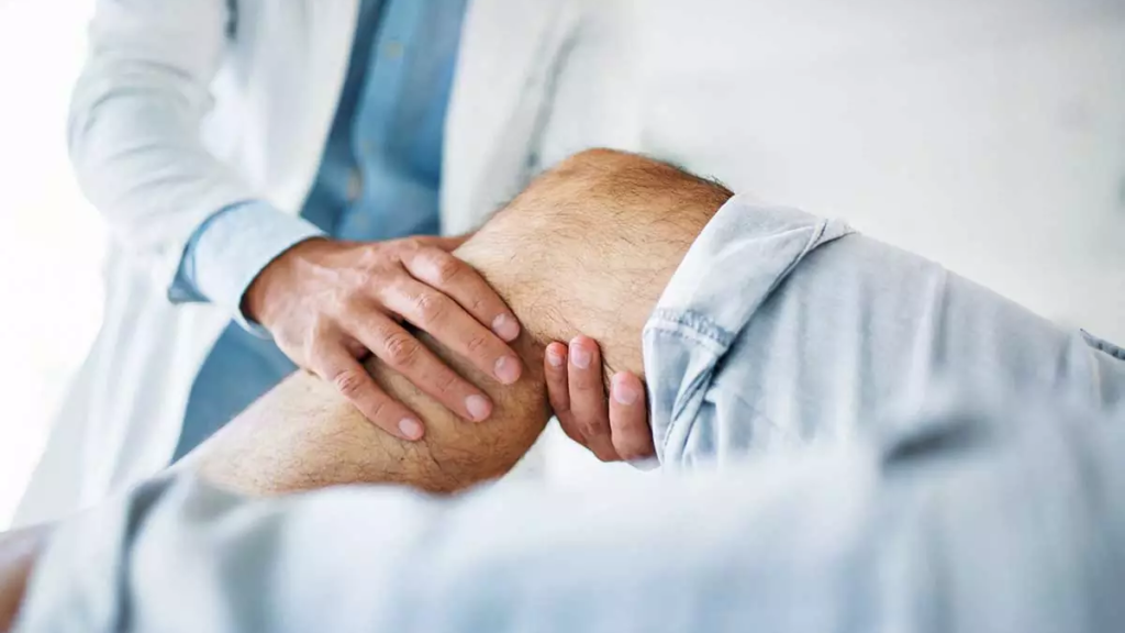 Fisioterapista esegue esercizi manuali al ginocchio di un paziente disteso
