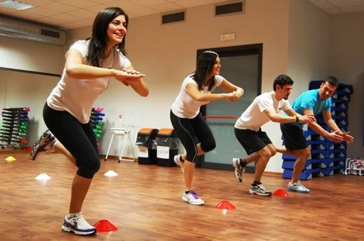 Uomini e donne che eseguono degli esercizi in palestra fisioterapica.