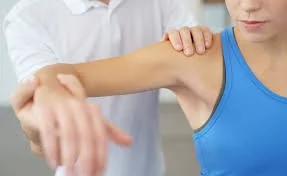 Fisioterapista che sostiene il braccio di un paziente durante una valutazione alla spalla