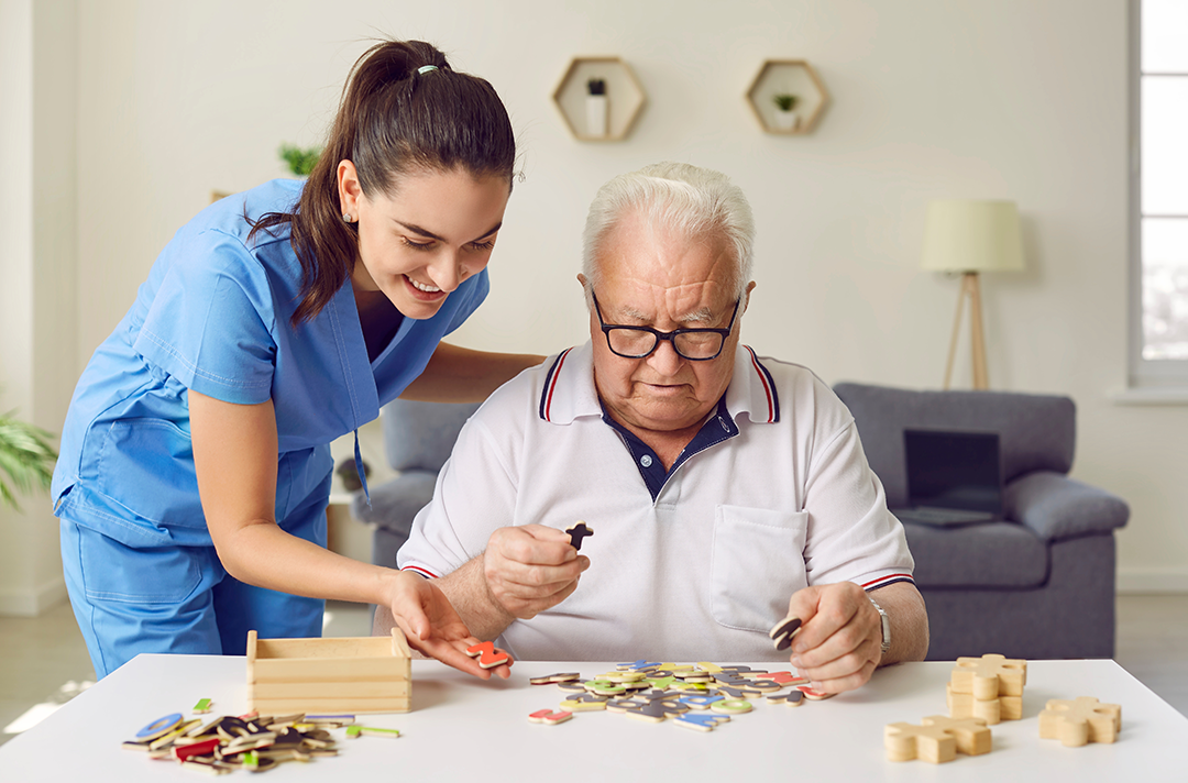 infermiera che aiuta un anziano negli esercizi neurocognitivi, come il puzzle