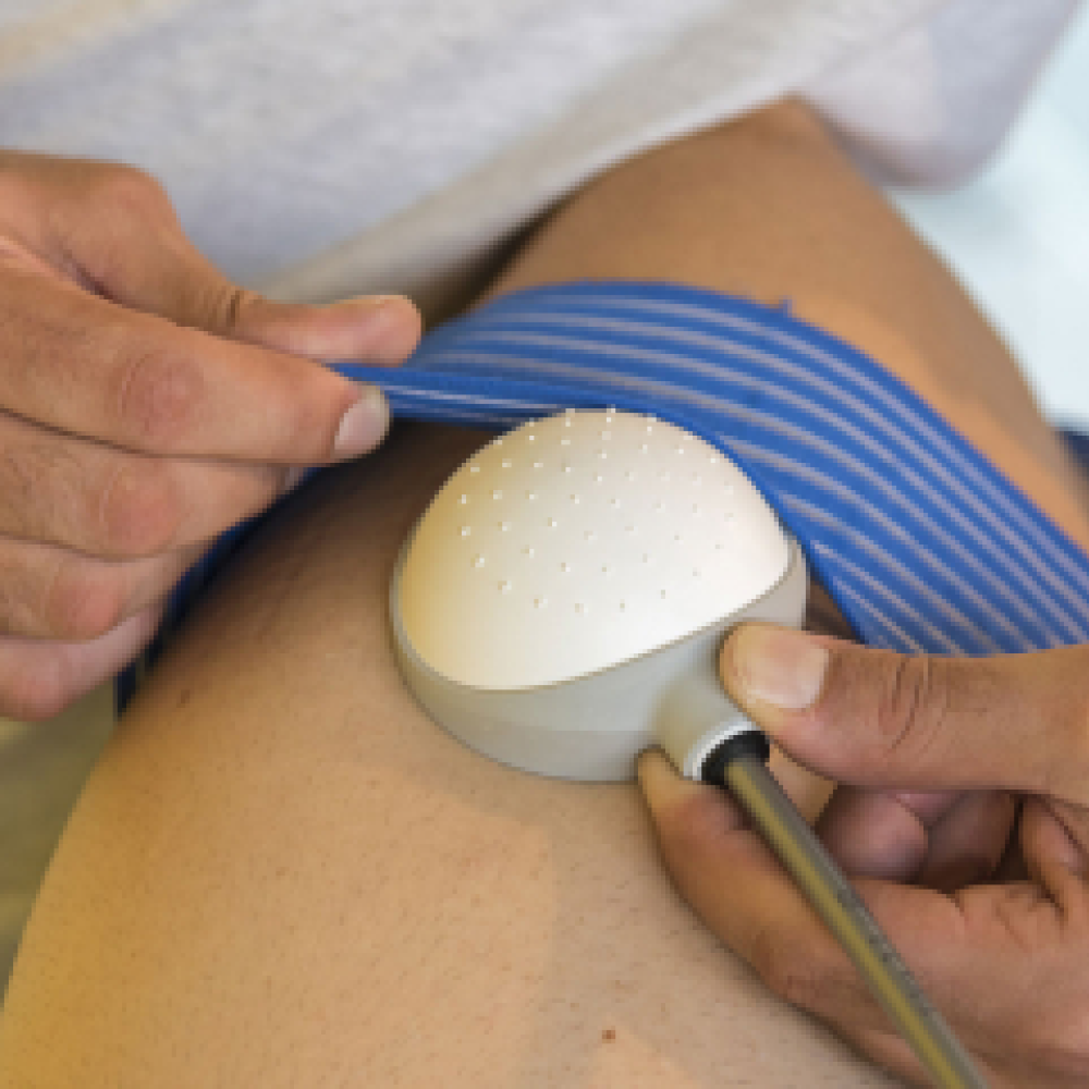 Dettaglio di una terapia fisica effettuata sul ginocchio di un paziente con dispositivo elettromedicale e fasce elastiche durante una seduta di Vibra 3.0