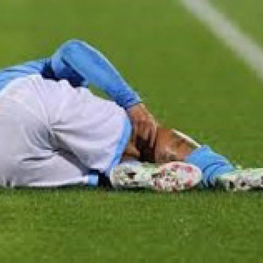 Calciatore a terra che si tiene il ginocchio infortunato durante una partita