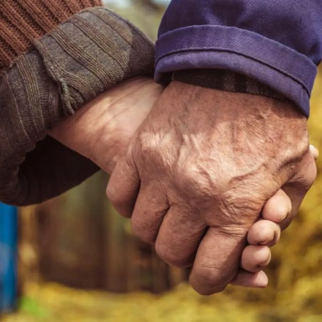 Primo piano di due mani anziane che si tengono, simbolo di affetto, cura e solidarietà
