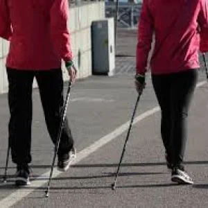 Due persone che praticano nordic walking su pista asfaltata con bastoncini da camminata