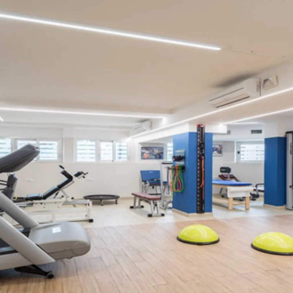 Palestra riabilitativa attrezzata con macchinari, lettini e strumenti per fisioterapia