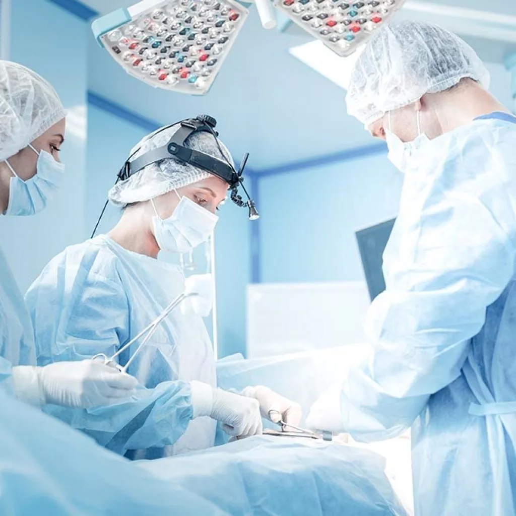 Chirurghi in sala operatoria impegnati in intervento ortopedico o spinale, con luci scialitiche e strumenti chirurgici sterili