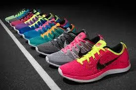 Fila ordinata di scarpe da corsa Nike colorate su una superficie scura accanto a una linea bianca